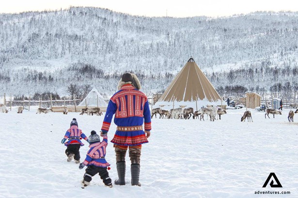 sami culture father with children walking near tents