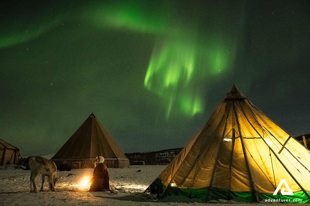 aurora borealis above sami culture tents in winter