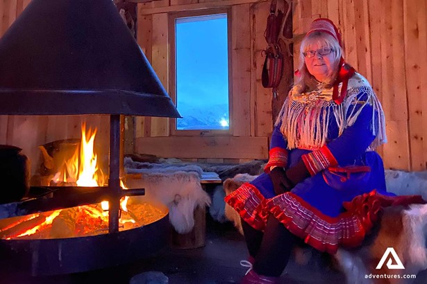 sami culture woman warming up near a fireplace