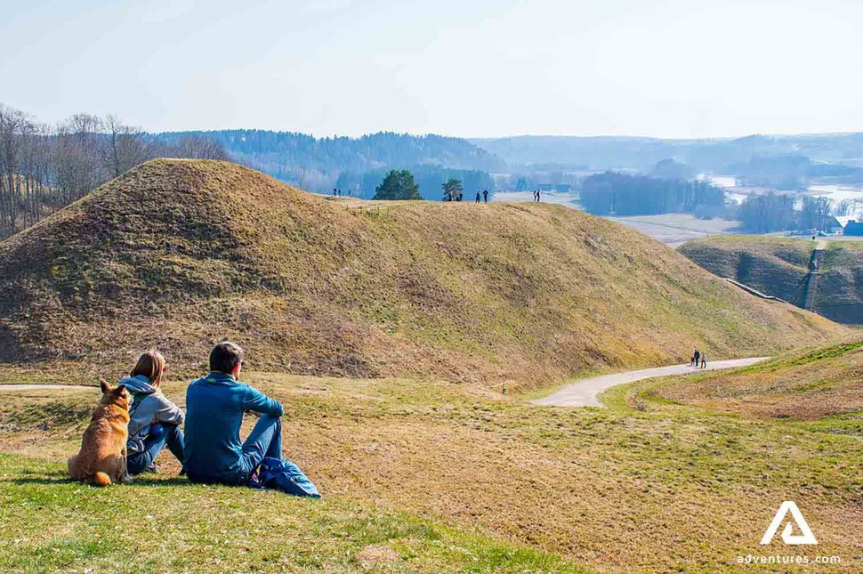 a couple with a dog resting near kernave hills in lithuania