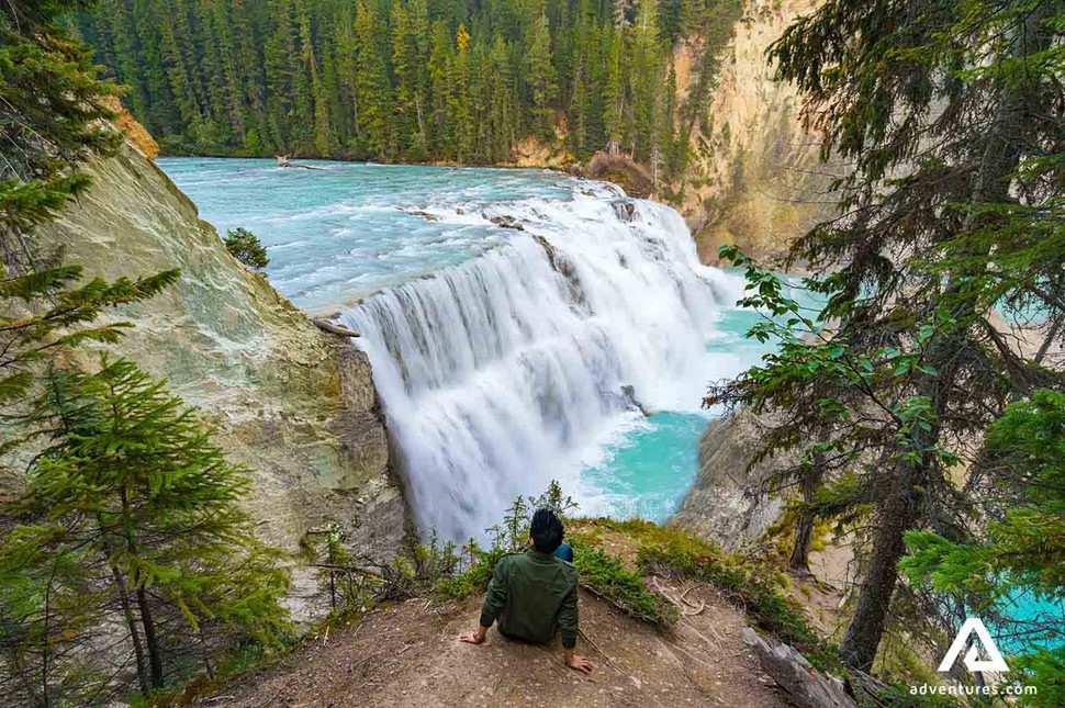 man sitting near wapta falls in yoho national park