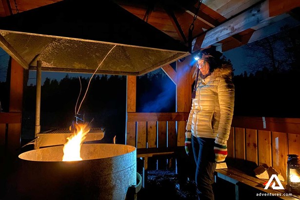 woman with a flashlight near a campfire in finland