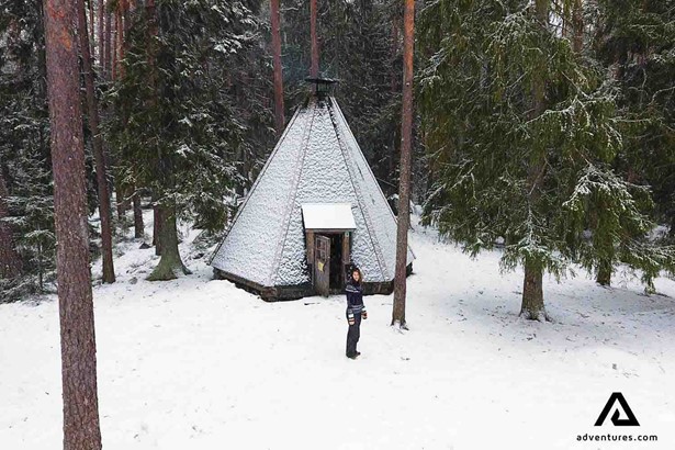 woman near a snowed up teepee tent in finland