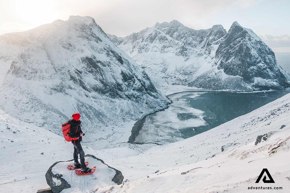 hiker snowshoeing on mountains in norway near a beach