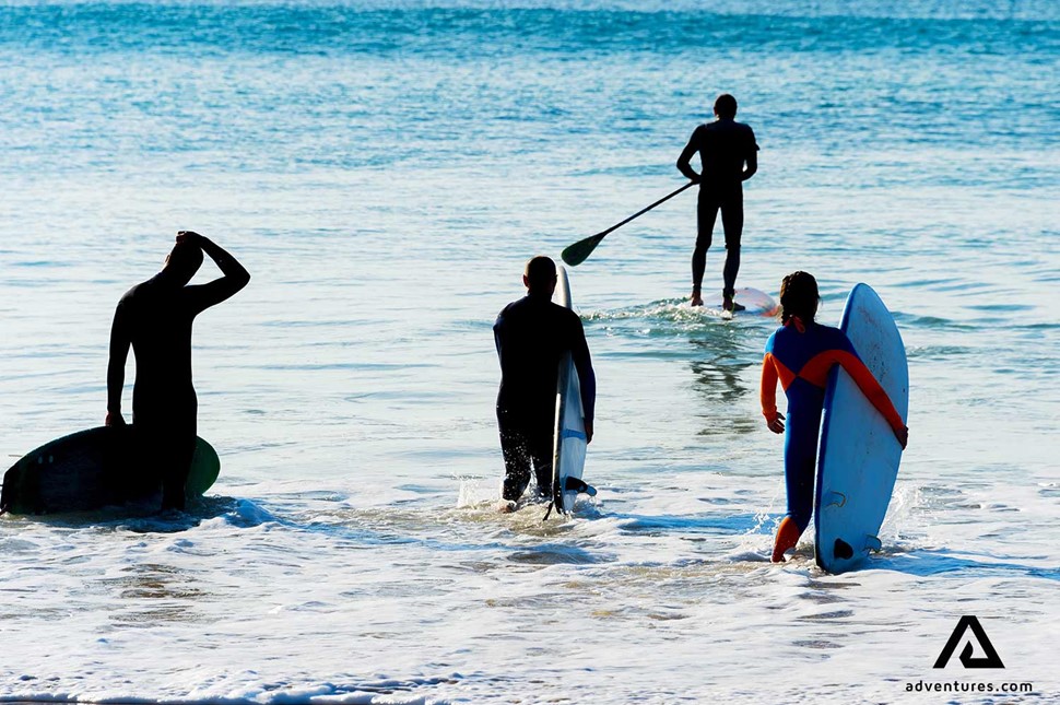 paddle boarders and surfers at a beach in summer