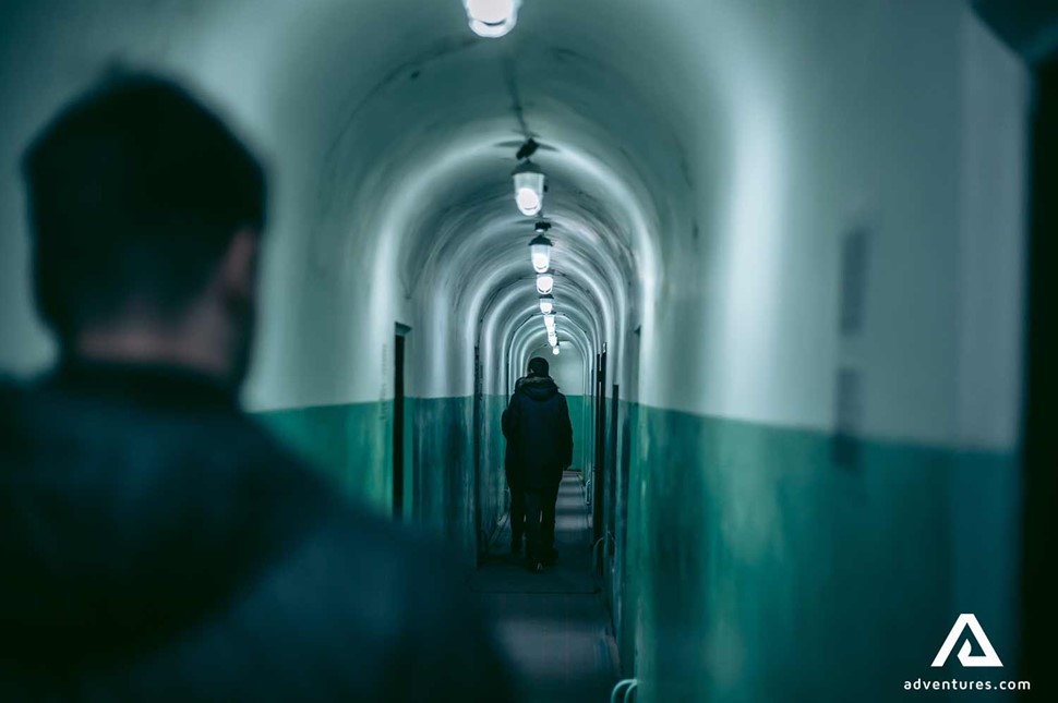 people walking down a dark soviet bunker underground