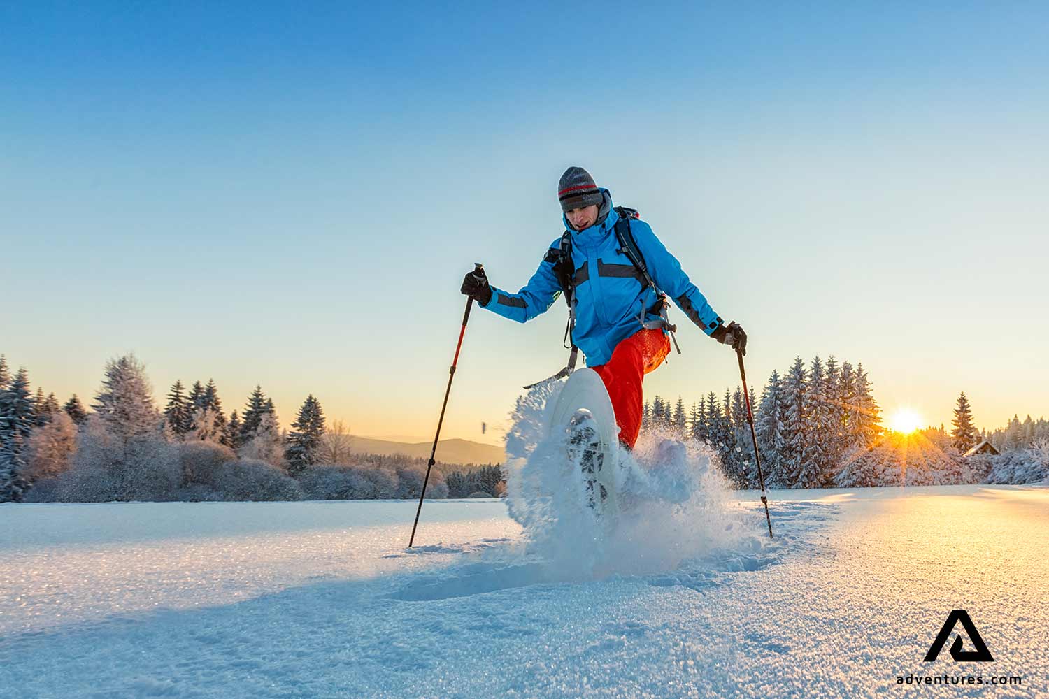 man snowshoeing in winter at sunset