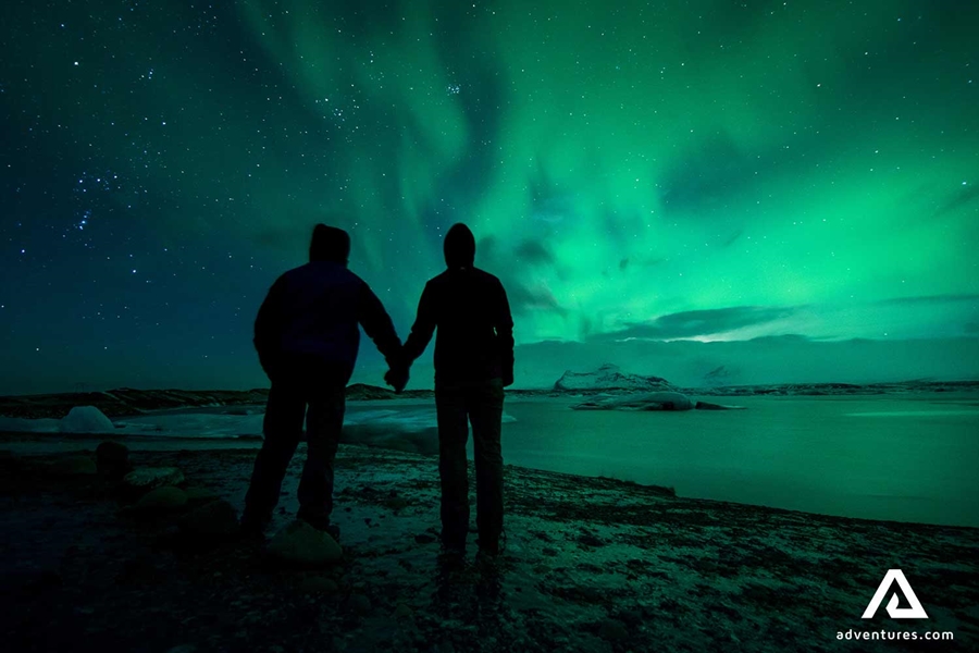 couple holding hands and watching northern lights