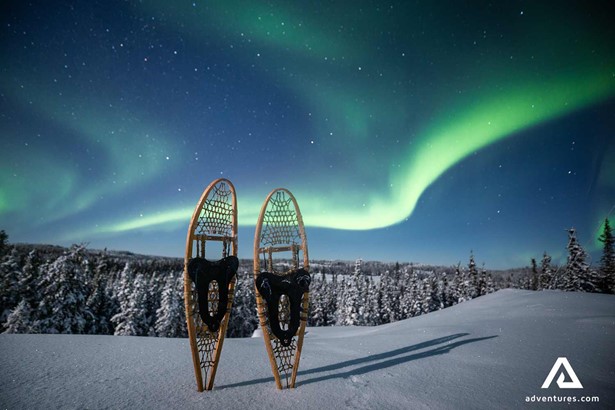 snowshoes in snow near northern lights
