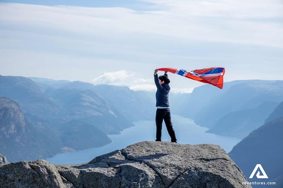 happy woman waving a norwegian flag near mountains