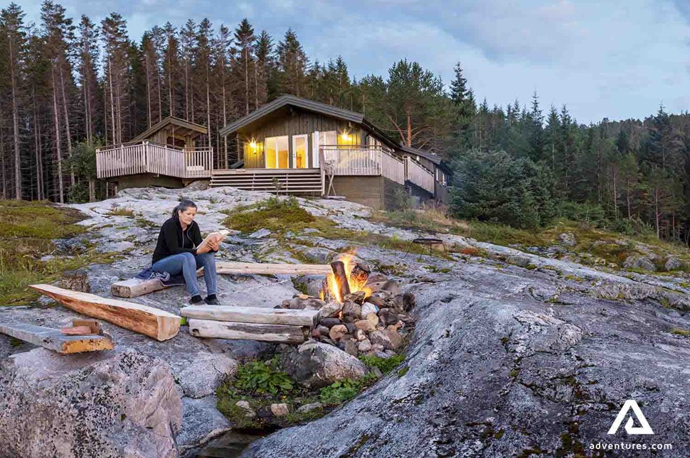 woman relaxing and reading a book near a campfire in norway
