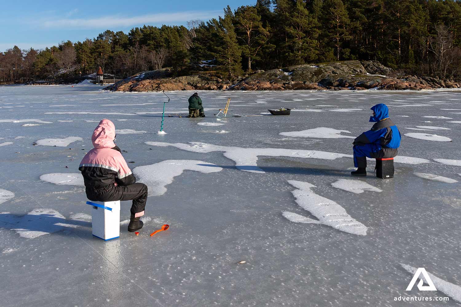 people ice fishing on a lake in winter