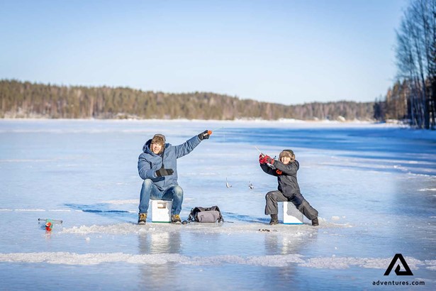 father and son ice fishing in winter