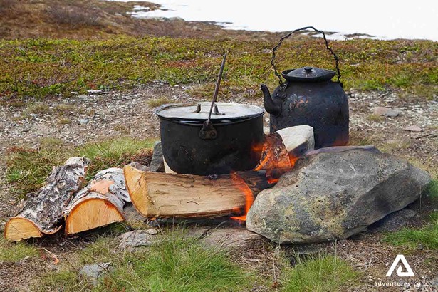 cooking food with large pots in a campfire