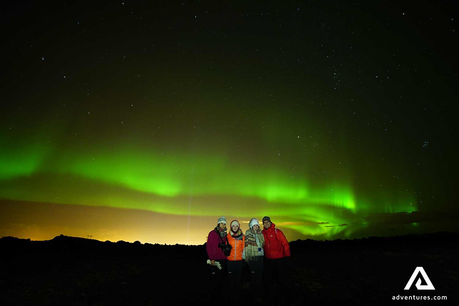 happy friends near northern lights