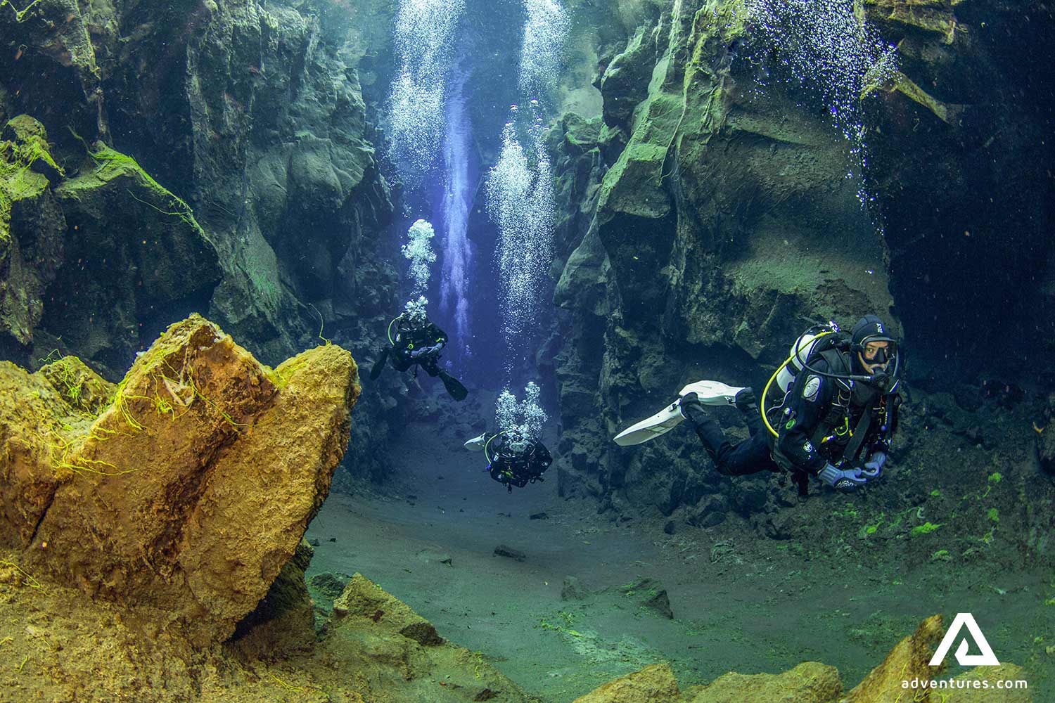 group of three people diving in clear water in thingvellir
