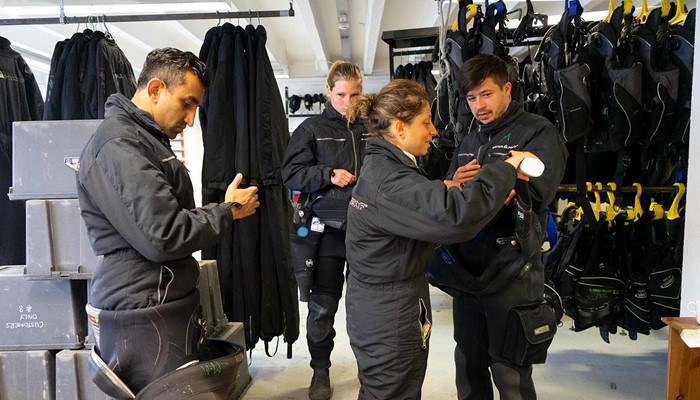 people getting ready for diving training in drysuits