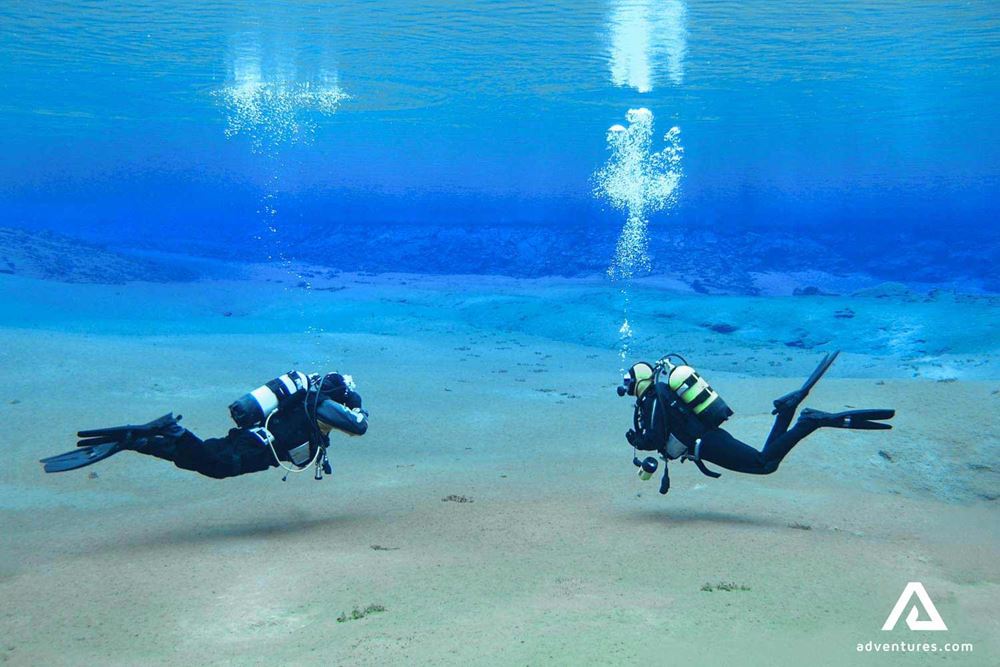 two divers making bubbles in clear blue water