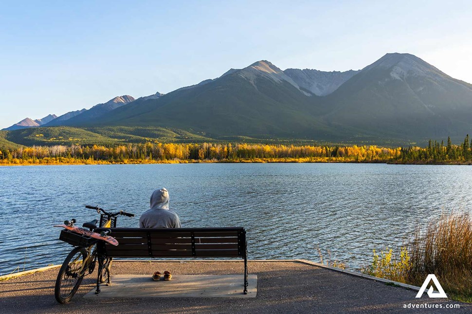 person sitting on a bench near a lake in the canadian rockies