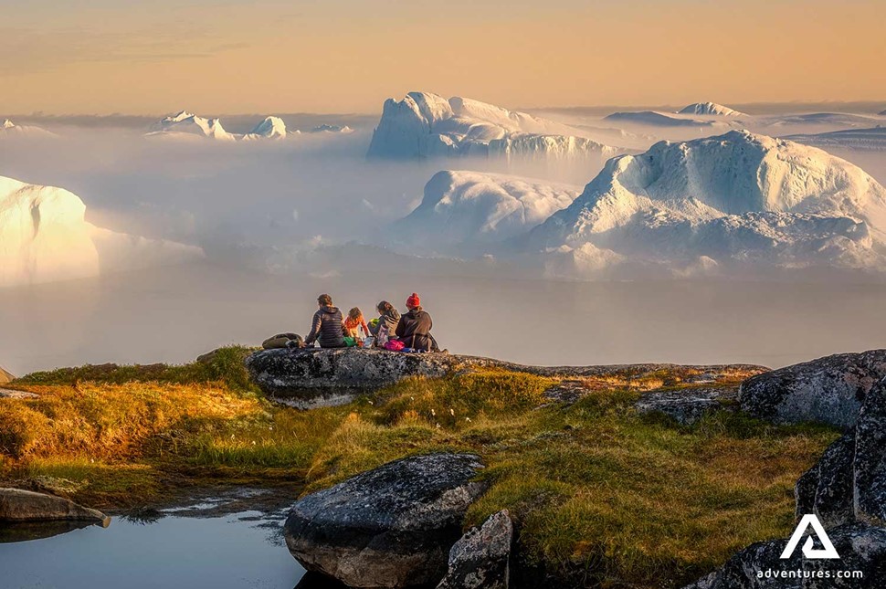 four people sitting looking at the icebergs