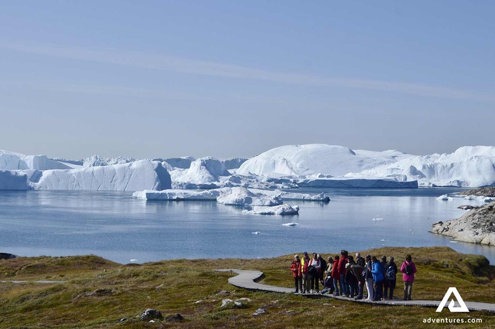 people walking near icebergs in greenland 