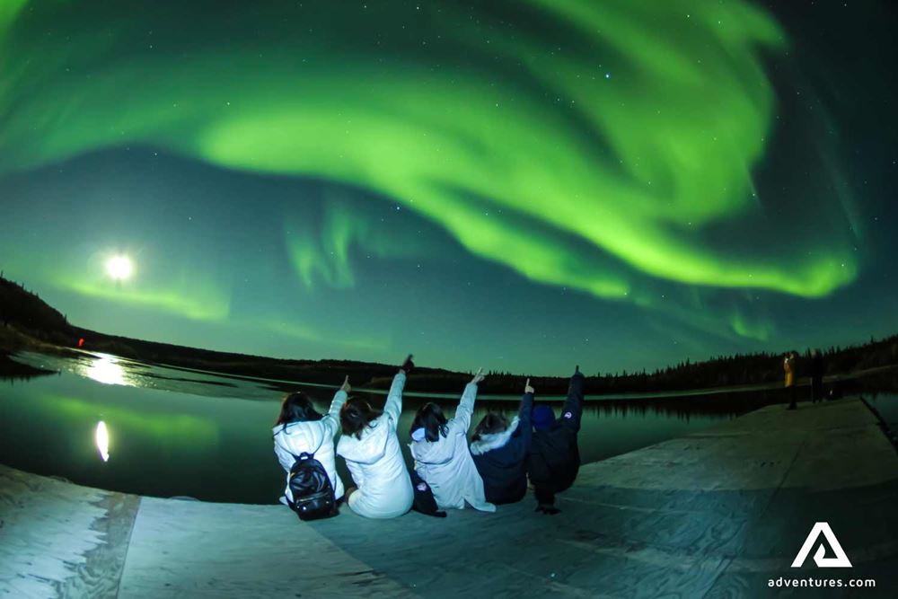 group of people pointing at northern lights