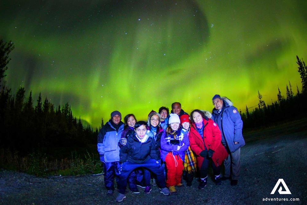 people taking a group photo with the northern lights