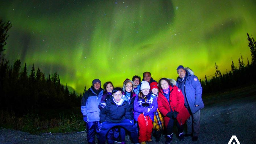 people taking a group photo with the northern lights