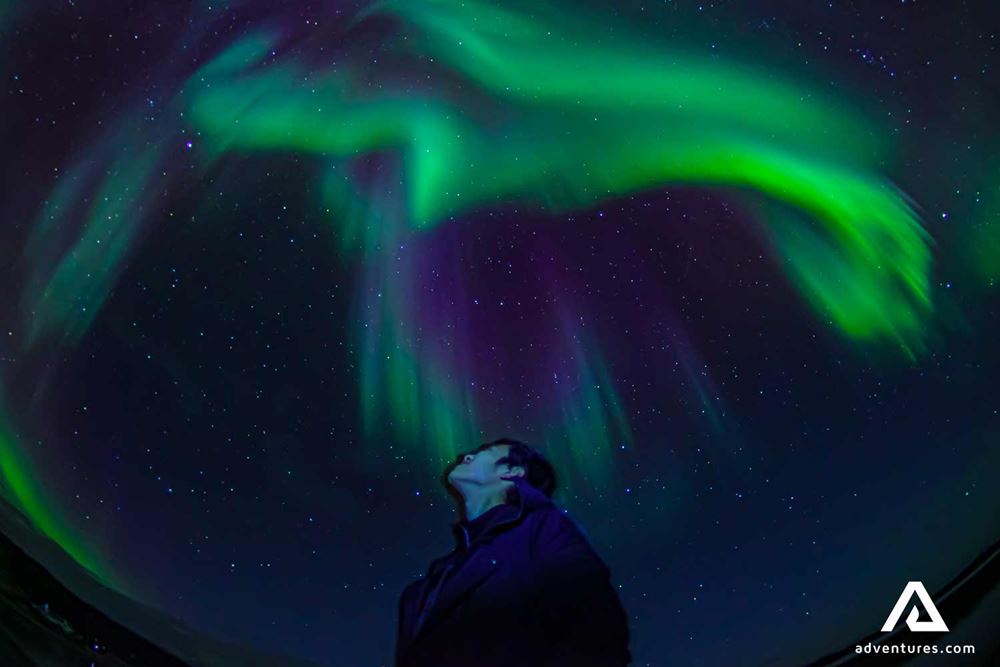 man looking at bright northern lights