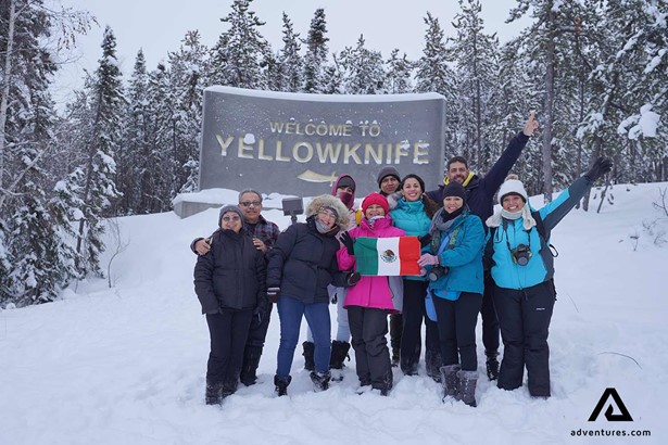 happy group posing with yellowknife city sign