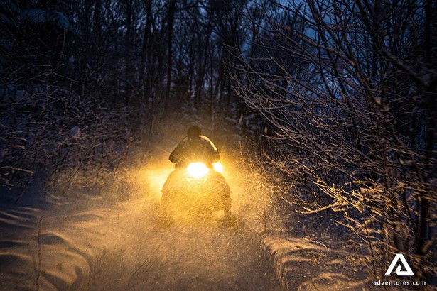 snowmobile lights at night in forest
