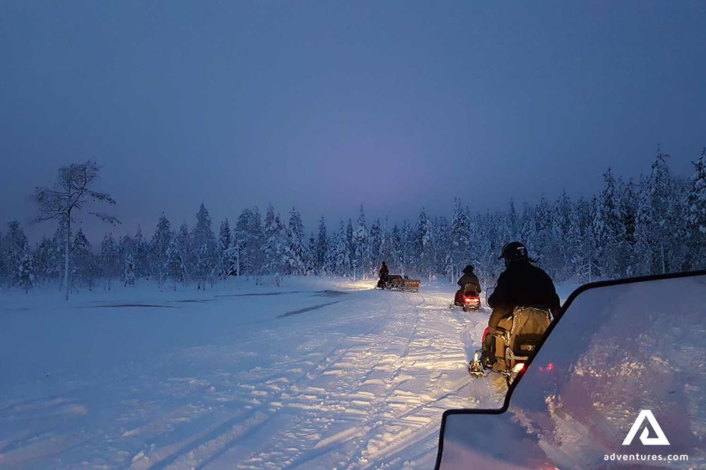 group of people snowmobiling in forest