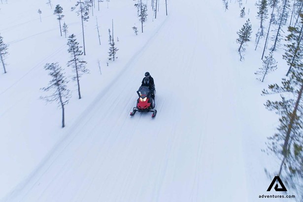 man snowmobiling in finland forest 