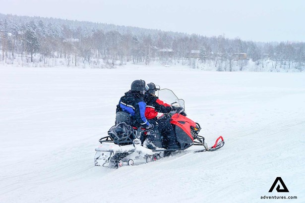 people snowmobiling on a frozen lake in finland 