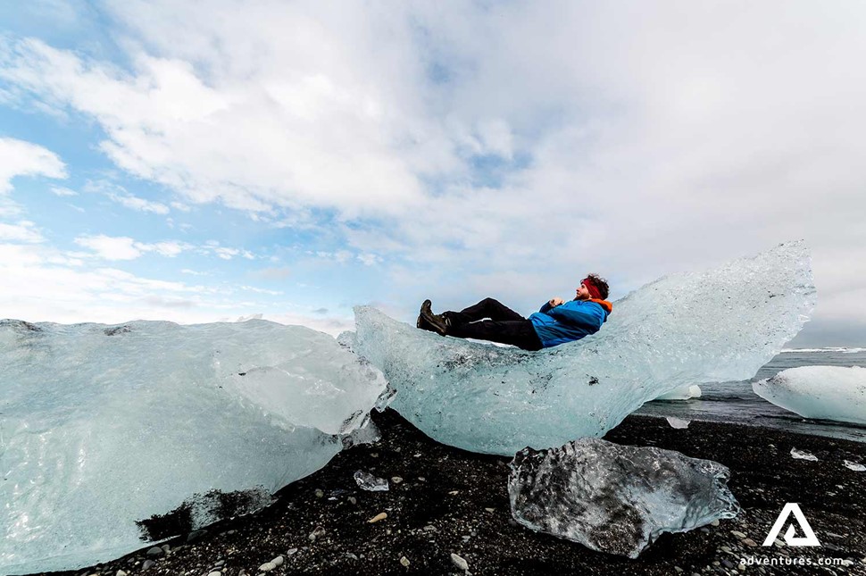 man laying on iceberg at diamond beach in iceland