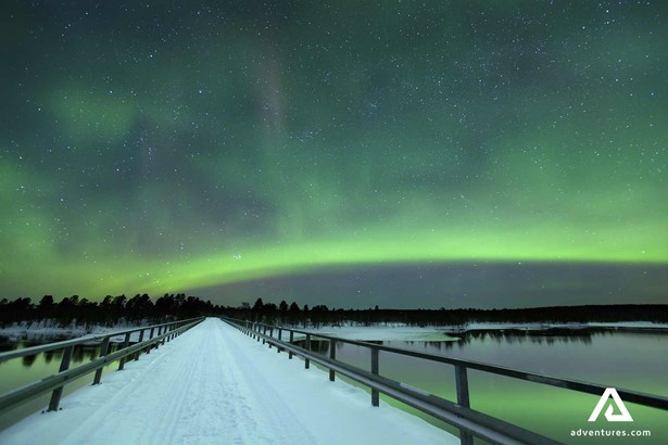 northern lights from snowy bridge in finland