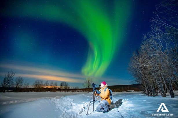 man taking pictures of aurora borealis in finland