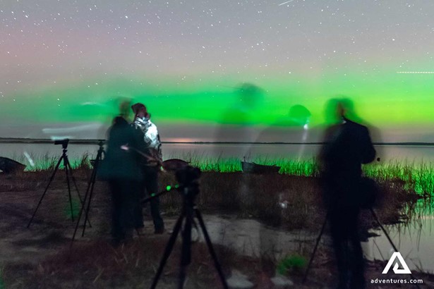 people posing with northern lights in finland