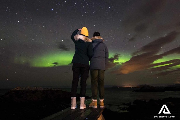 two friends watching northern lights in norway