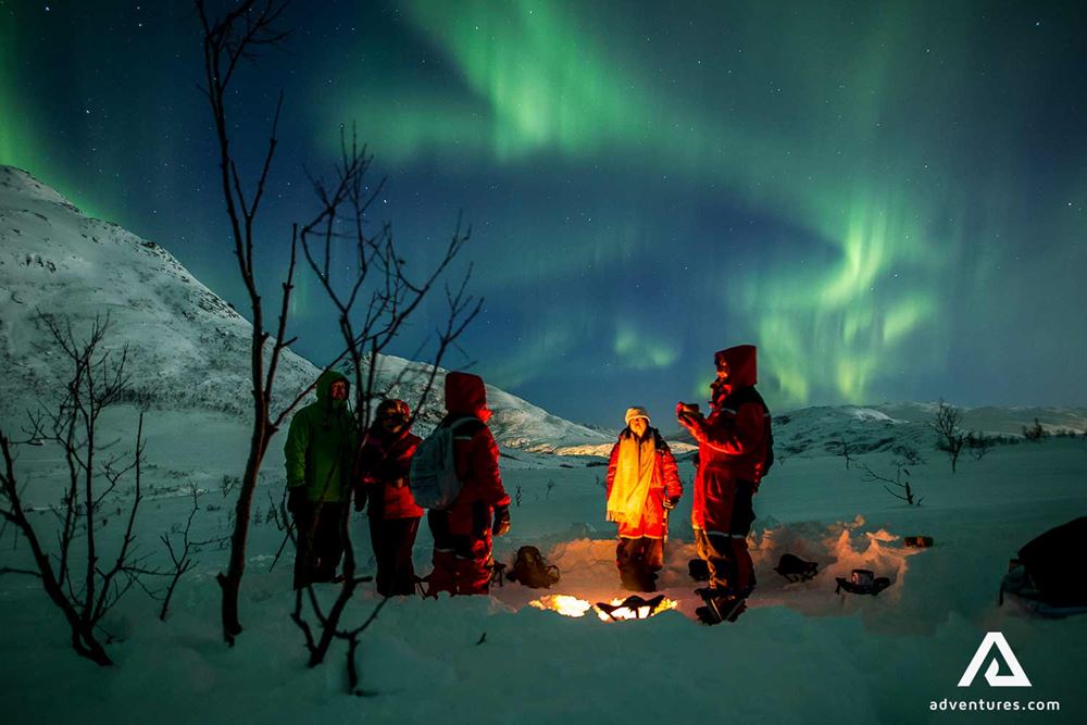 group by campfire watching northern lights in norway