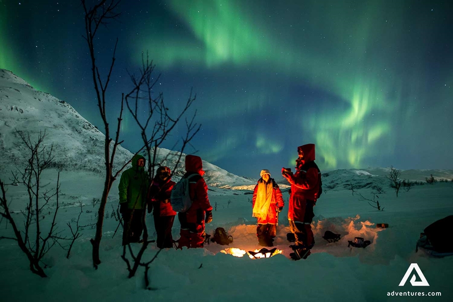 group by campfire watching northern lights in norway