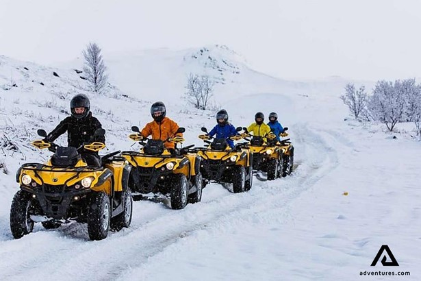friends driving quad bikes on winter in finland
