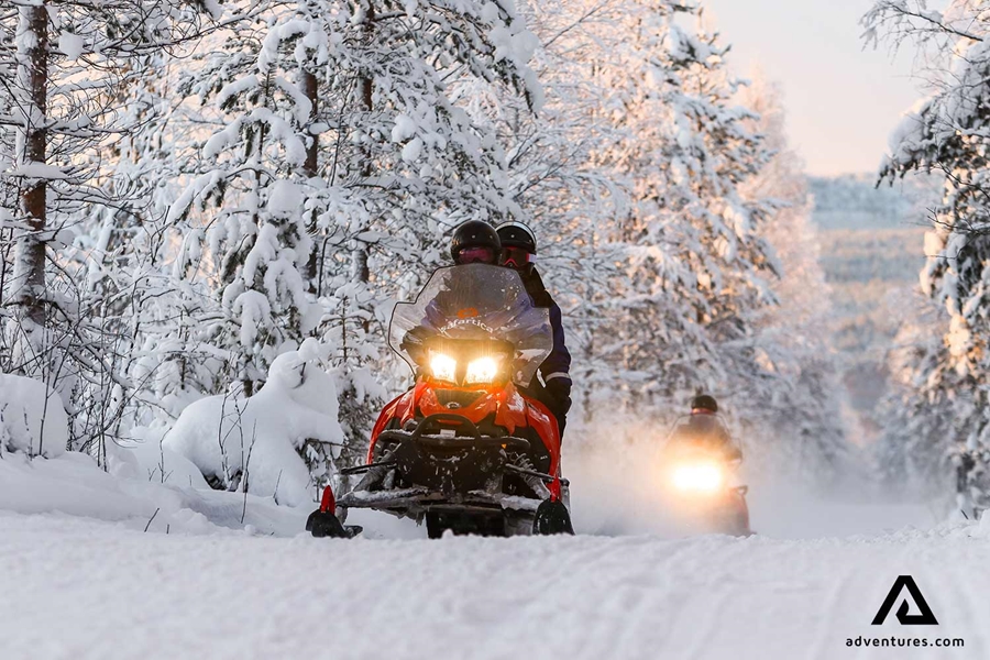 snowmobiling in forest full of snow