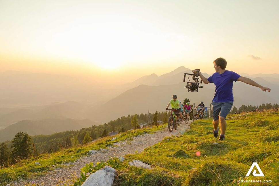 man running with a camera filming mountain bikers