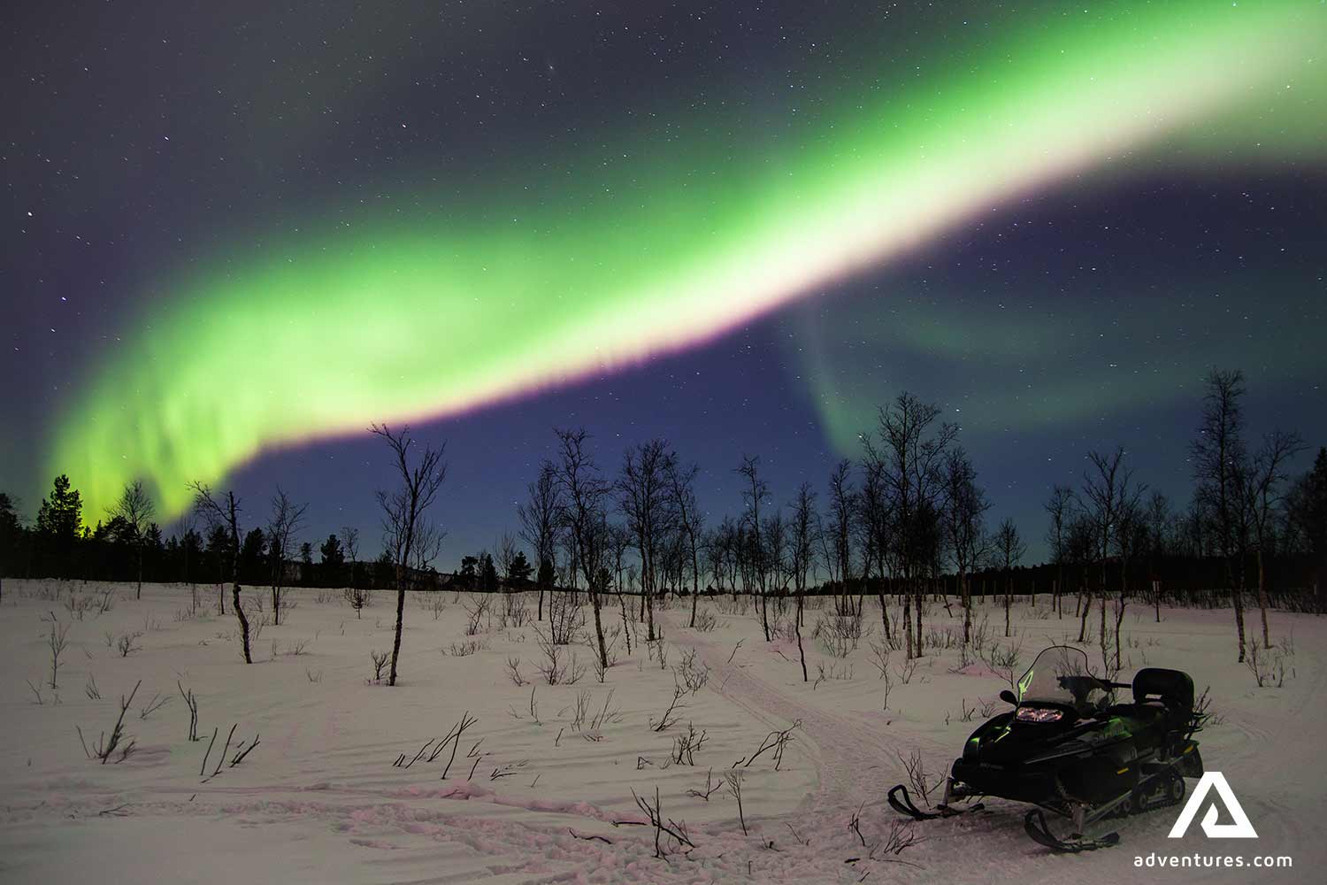 bright Northern Aurora over snowmobile in winter