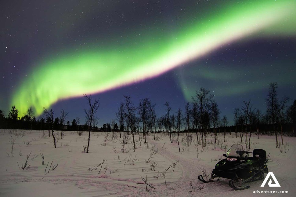 bright Northern Aurora over snowmobile in winter