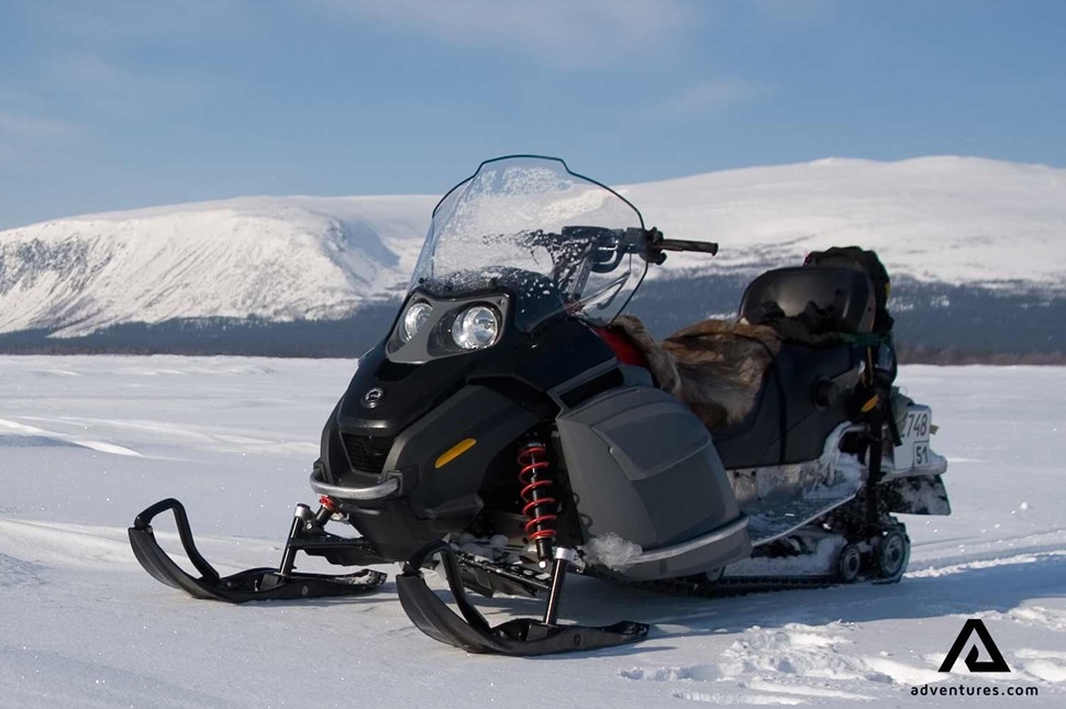 black snowmobile near mountains in Finland