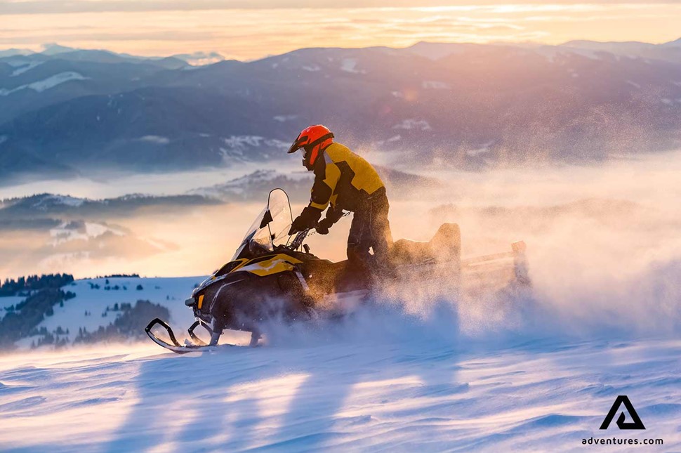 man snowmobiling down the mountains in Finland