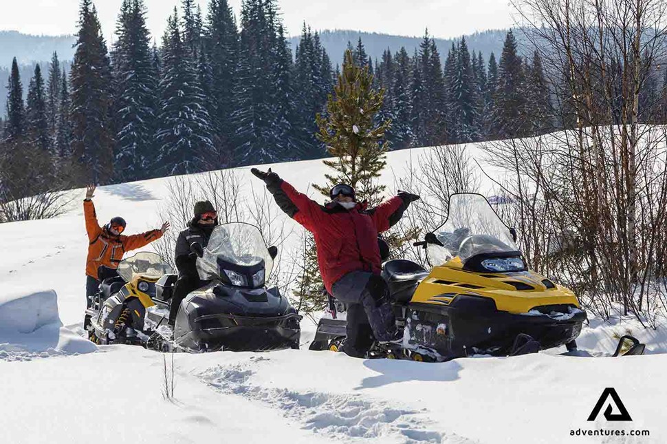 happy friends snowmobiling in Finland on winter