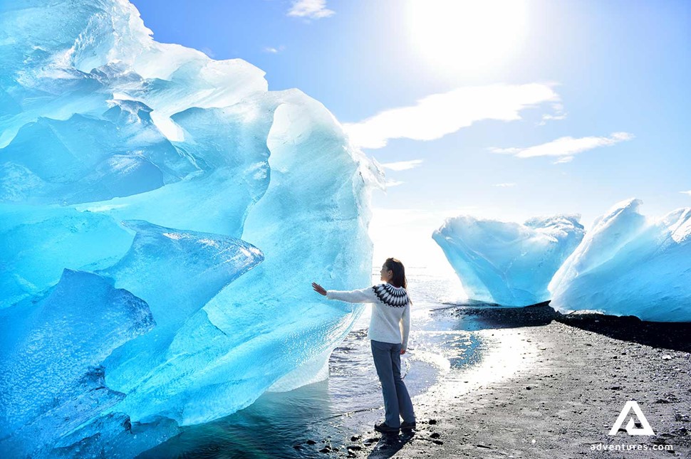 woman touching huge iceberg in Iceland